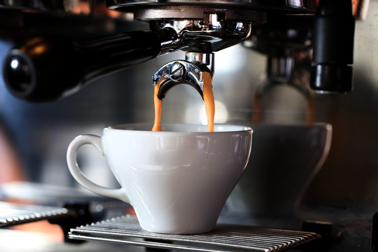 Close-up of espresso pouring from a coffee machine into a white ceramic cup.
