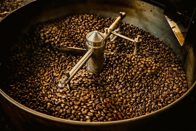 Freshly roasted coffee beans cooling in a commercial drum roaster with metal stirring arms.